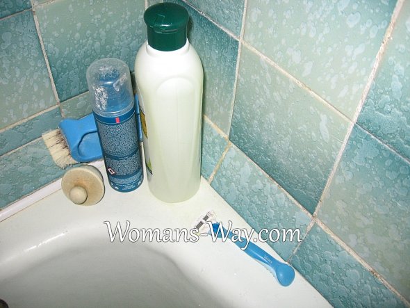 Скопление моющих средств и принадлежностей на полочках в ванне