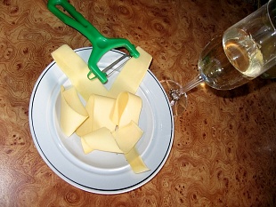 Тонко красиво порезанный твердый сыр на тарелке